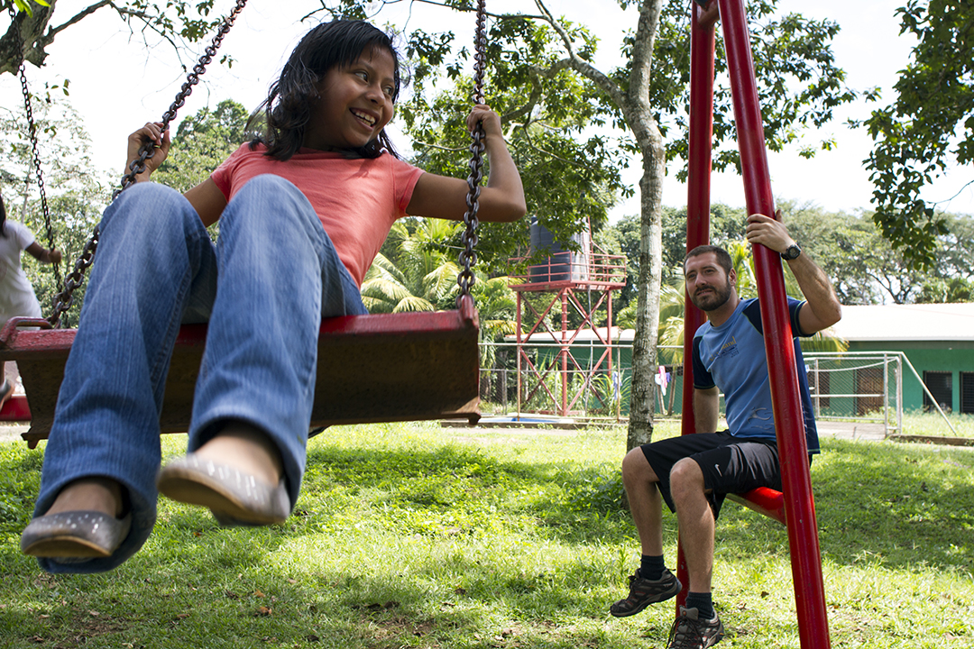 A volunteer watches as a child swings